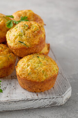 Homemade zucchini muffins with cheese, garlic and herbs on a plate on a gray concrete background. Vegetarian dish. Copy space.
