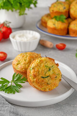 Homemade zucchini muffins with cheese, garlic and herbs on a plate on a gray concrete background. Vegetarian dish. Copy space.