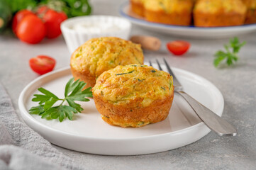 Homemade zucchini muffins with cheese, garlic and herbs on a plate on a gray concrete background. Vegetarian dish. Copy space.