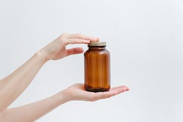 Medical empty brown glass bottle with cap in hands. Mokup, white background.  Alternative  and...