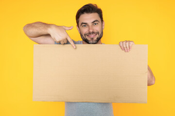 Handsome man holding empty board and pointing finger on board. Guy showing blank board with...