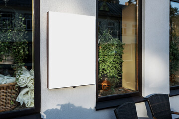 Advertising white blank poster mounted on hotel restaurant wall. Empty commercial display with copyspace for mockup information outside.