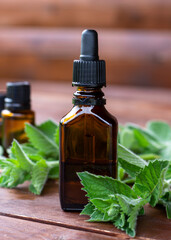 Peppermint essential oil. A dark (brown) glass bottle with mint essential oil and fresh mint on wooden table