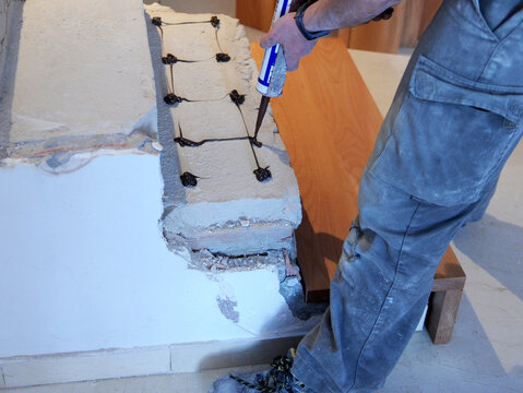 Carpintero preparando con silicona de alta resistencia la escalera de una casa para pegar los escalones de madera de haya. Trabajos de carpinter&iacute;a e interiorismo
