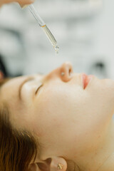 The cosmetologist makes an injection in the lips of a girl for an increase in the cosmetology office with a syringe close-up face