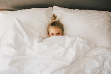 Cute little girl having fun lying in bed.
