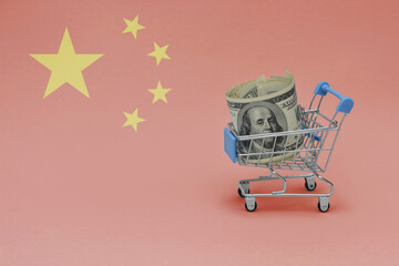 Metal shopping basket with dollar money banknote on the national flag of china background. consumer...