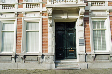 Fototapeta na wymiar Entrance to a luxury mansion with a green door and white window frames in Breda in the Netherlands