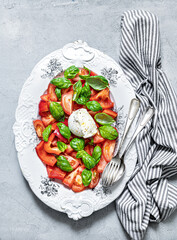 Tomatoes, bell pepper, mozzarella and basil Salad. Bread, olive oil, cutlery. Healthy mediterranean food.  Caprese. Appetizing laid table. Top view.