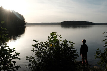 young boy enjoys stunning light and landscape scene at lake stechlin