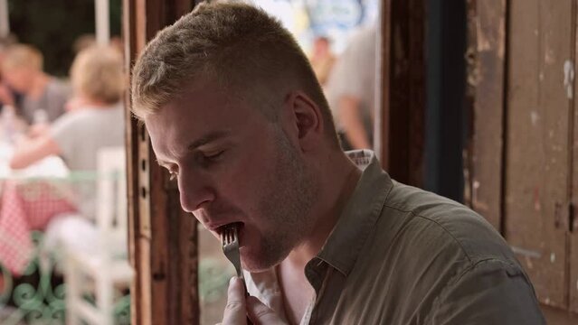 Caucasian middle-aged blond man enjoying eating rare beef steak in authentic restaurant.Person having delicious and tasty meal.