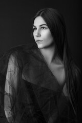 Fashion portrait of a beautiful caucasian model in her 20s. She is wrapped in tulle fabric. The...