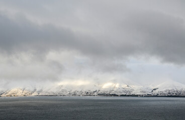 Incredible scenic view to Lake Sevan surrounded by mountains covered snow under low snowy clouds. Lake Sevan is the main pearl of the Armenian nature
