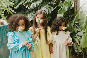 Three little girls in the garden with flowers in their hands. children of different nationalities.