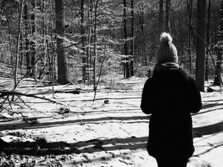 young woman hiking on frozen path on a cold sunny winter day in black and white