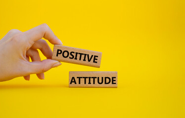 Positive attitude symbol. Concept words Positive attitude on wooden blocks. Beautiful yellow background. Businessman hand. Business and Positive attitude concept. Copy space.