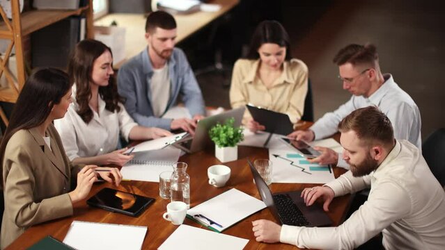 Top view of employees, colleagues, business people at meeting in office, sitting at table with papers, documents and working, discussing. Business, career development, brainstorming, teamwork concept