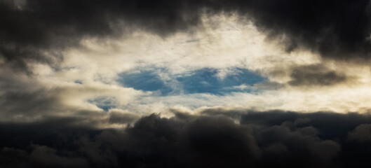 A dramatic sky with dark clouds, through which a piece of blue sky can be seen