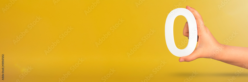 Leinwandbilder numeral zero in hand. a hand holds a white number zero on a yellow background with copy space. zero 