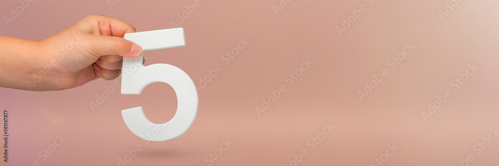 Aufkleber number five in hand. hand holding white number 5 on red background with copy space. concept with num