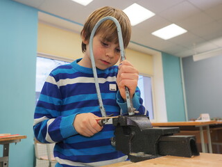 boy with red hair in a blue sweater is making a boat out of Styrofoam