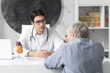 Aged man visiting young male doctor cardiologist in modern clinic