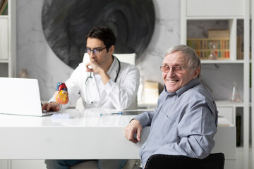 Obraz premium Portrait of a smiling elderly man sitting at a table on examination by a cardiologist