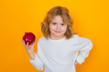 Fototapeta na wymiar Vitamin and healthy fruits for kids. Kid hold red pomegranate in studio. Pomegranate fruit. Studio portrait of cute child with pomegranate isolated on yellow background.