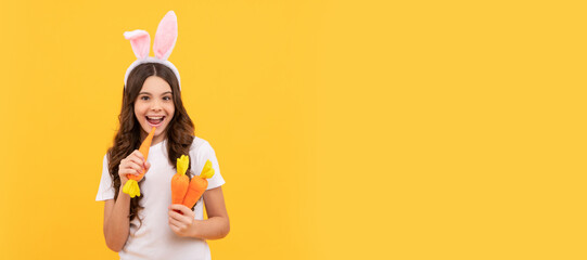 happy hungry teen girl in bunny ears hold carrot on yellow background, easter. Easter child...