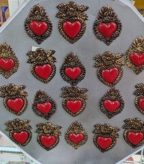 Red and golden mexican tin hearts on gray wall