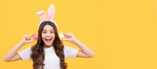 surprised kid in bunny ears hold eggs on yellow background. Easter child horizontal poster. Web...