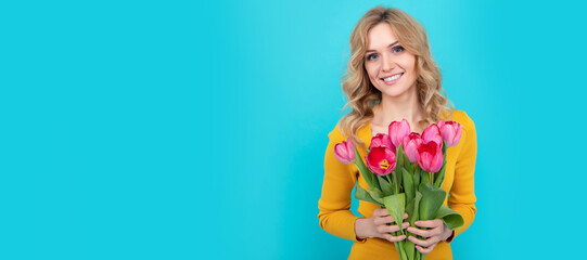 happy young blond woman with spring tulip flowers on blue background. Woman isolated face portrait, banner with mock up copy space.