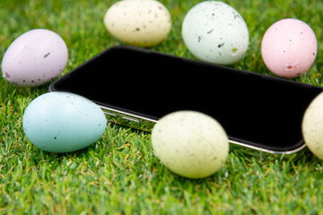 Phone with blank empty screen on background of easter eggs with  in  on green grass. Space for text. Happy Easter! Smartphone mockup,