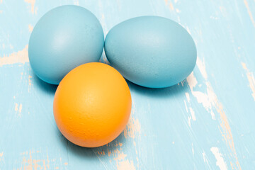 Eggs symbolizing the Easter holiday in blue and orange color on a background of aged wood