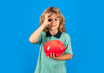 Saving money concept. Kid putting coin into piggy bank for saving with pile of coins. Piggybank with coins and child concept.