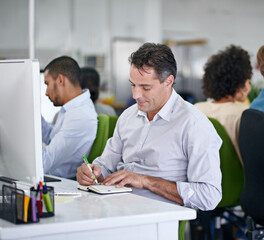 Details are worth writing down. a group of creative businesspeople working on computers in the office.