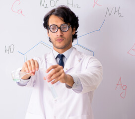 Young funny chemist in front of white board