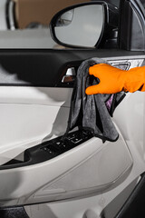 Hand car interior drying of car door card panel using microfiber in detailing auto service. Cleaner worker dry car interior.