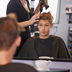 Hes in for a trendy cut. a young man having his hair styled by a hairdresser.