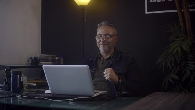 Freelancer man jumping with excitement in front of his screen fter receiving good news on his laptop.