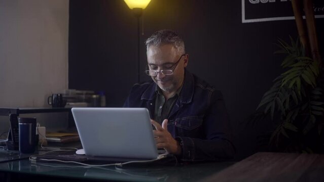 Freelancer man jumping with excitement in front of his screen fter receiving good news on his laptop.