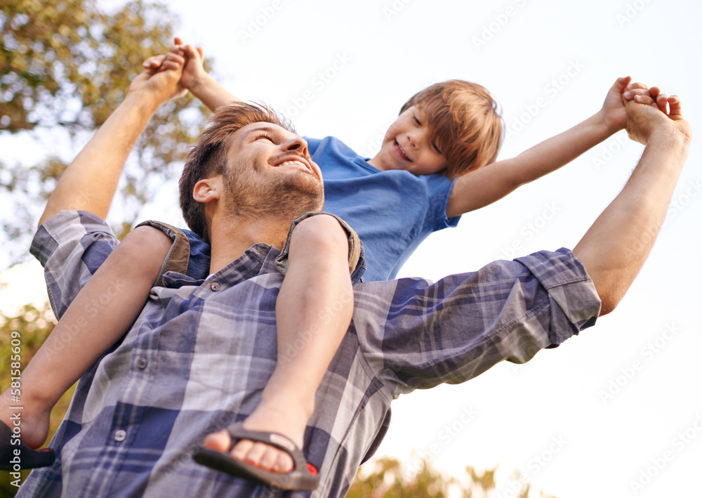 Wall mural He loves his little boy so much. a young father carrying his son on his shoulders.