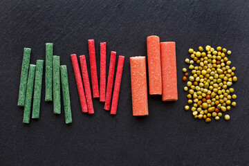 Fertilizer sticks or spikes and granules for long-term fertilization for better plant growth, in red, green, yellow and orange, on dark background.