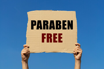 Paraben free text on box paper held by 2 hands with isolated blue sky background. This message board can be used as business concept about paraben free.