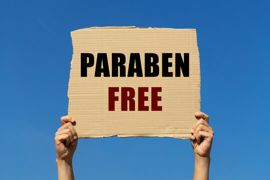 Paraben free text on box paper held by 2 hands with isolated blue sky background. This message board can be used as business concept about paraben free.