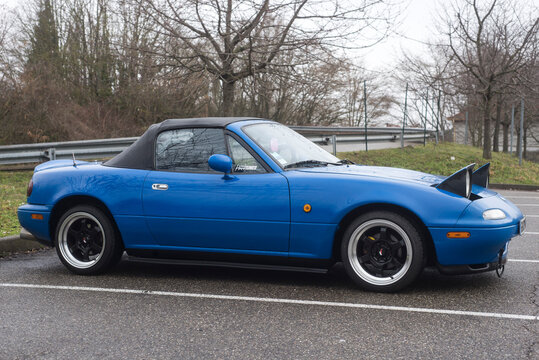 Mulhouse - France - 11 March 2023 - Profile view of vintage Mazda MX5 parked in the street by rainy day