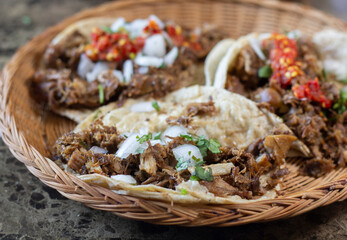 plate with 3 tacos of pork carnitas with red sauce. Mexican food