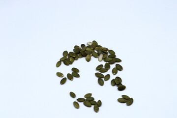 Green pumpkin core seeds on a white background.