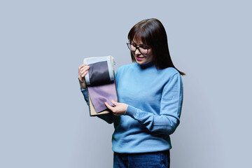 Woman designer holding book with fabrics, on light background