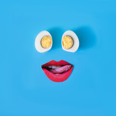 Two half eggs and red lips on blue background. Minimal surreal concept for Easter celebration banner or card. Design for wallpaper. Copy space. Flat lay.